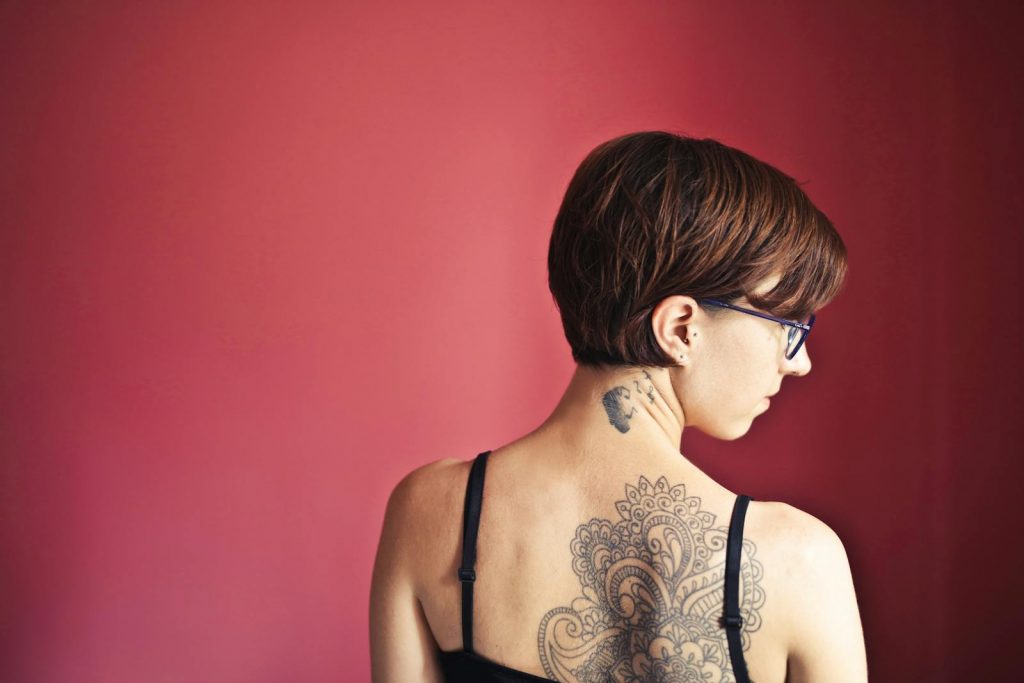 Rückenansicht einer Frau mit Mandala-Tattoo auf der Schulter.