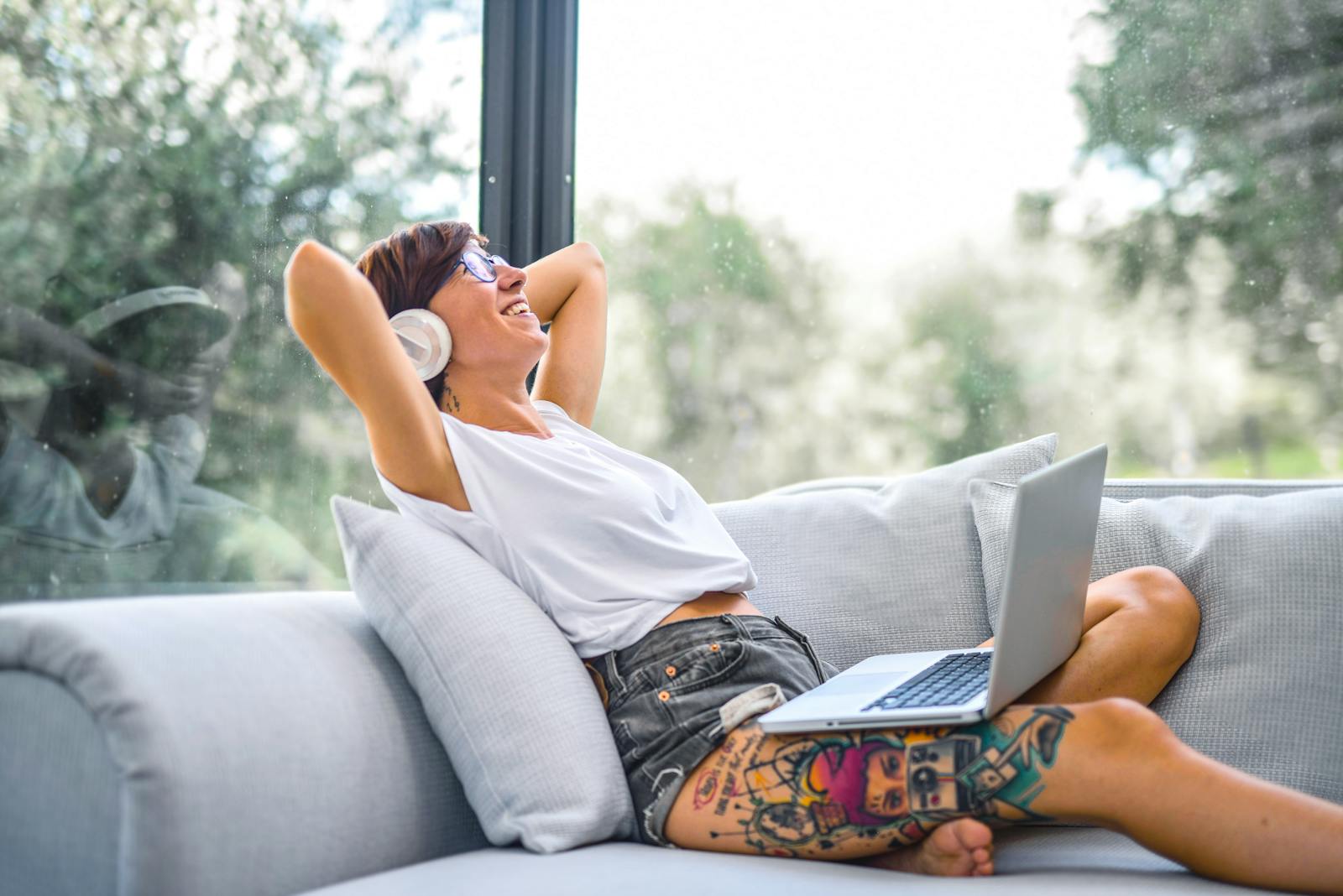 Eine Frau sitzt auf einem Sofa, auf dem Oberschenkel ist ein großes farbiges Oberschenkel-Tattoo zu sehen.