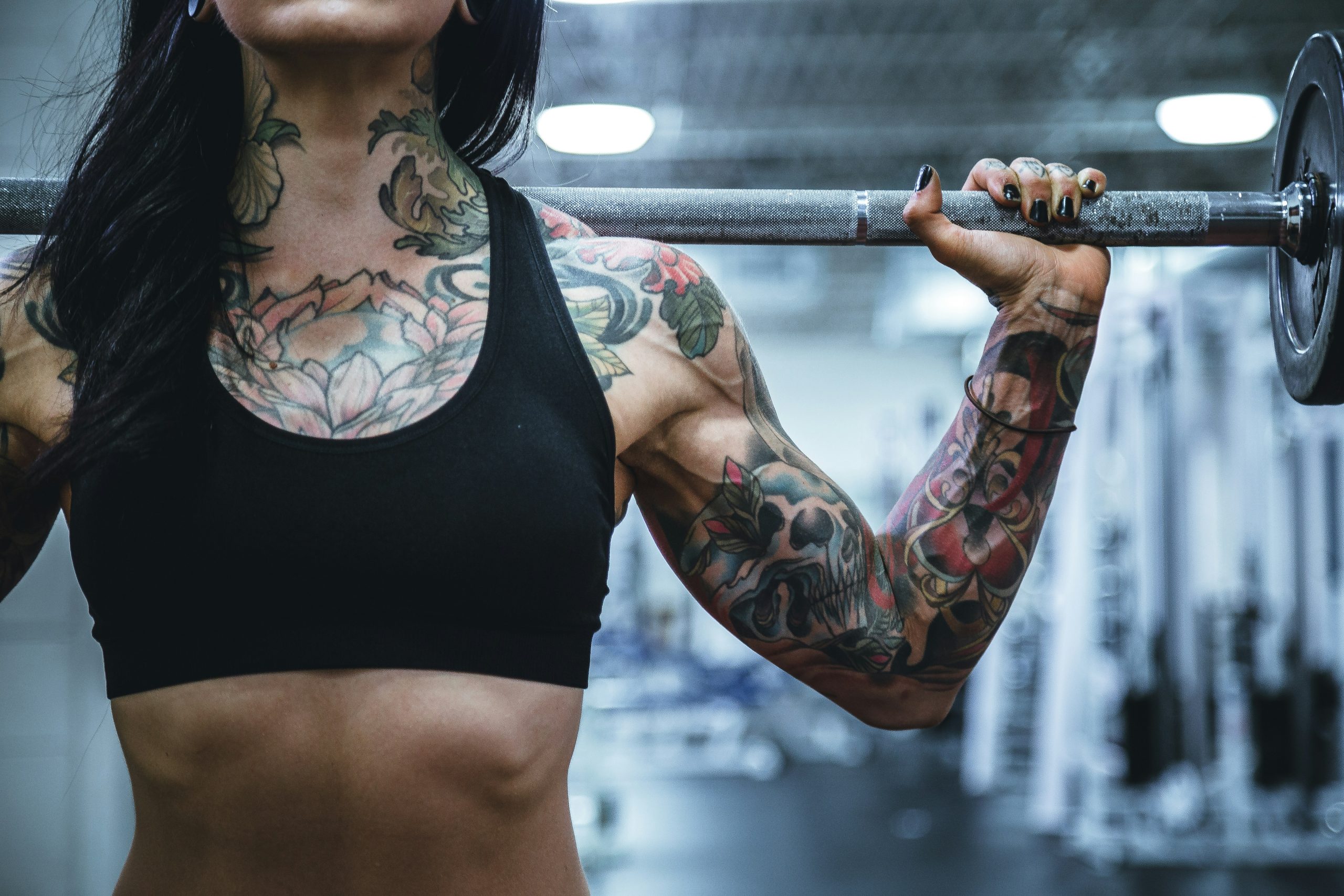 Nahaufnahme einer Frau, die mehrere farbige Tattoos auf Oberarm, Unterarm und Brust hat.