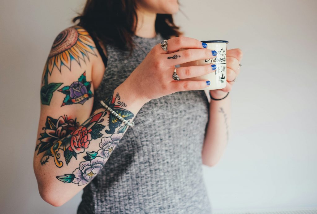 Nahaufnahme einer Frau, die mehrere farbige Tattoos am Arm hat.