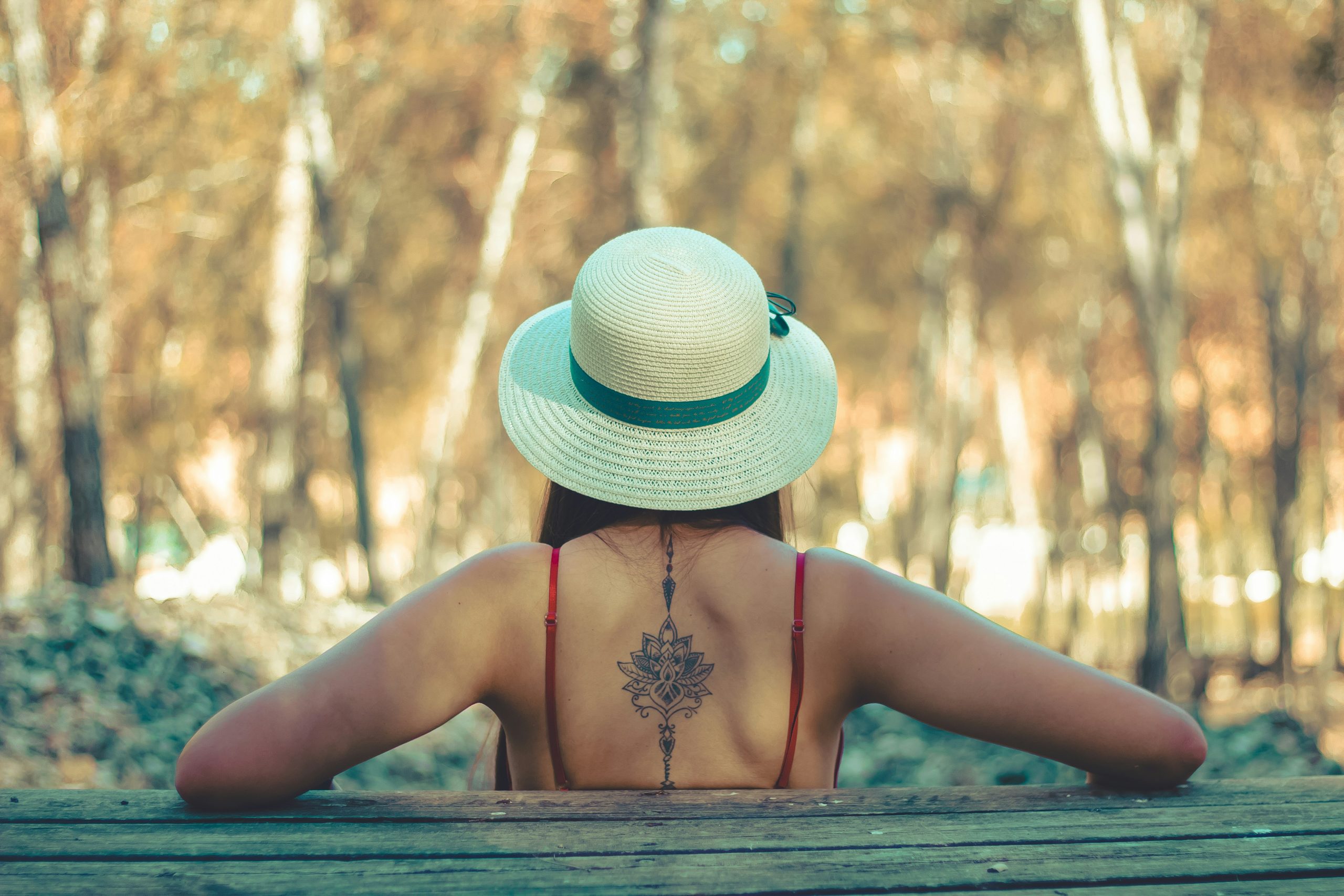 Rückenansicht einer Frau, die ein Mandala-Tattoo auf dem Rücken im Bereich der Wirbelsäule hat.