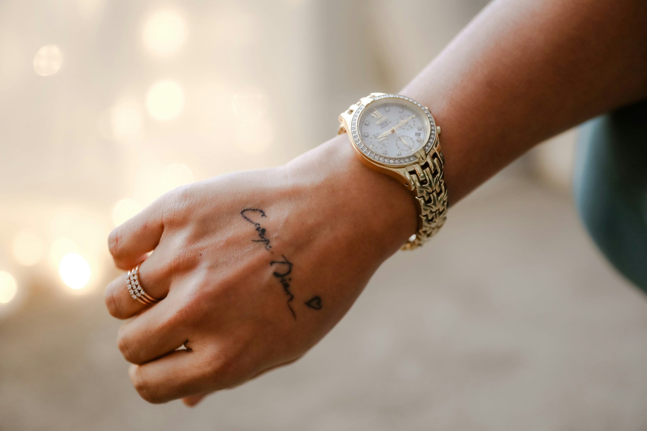 Nahaufnahme einer Hand, die einen Schriftzug als Tattoo auf dem Handrücken hat.