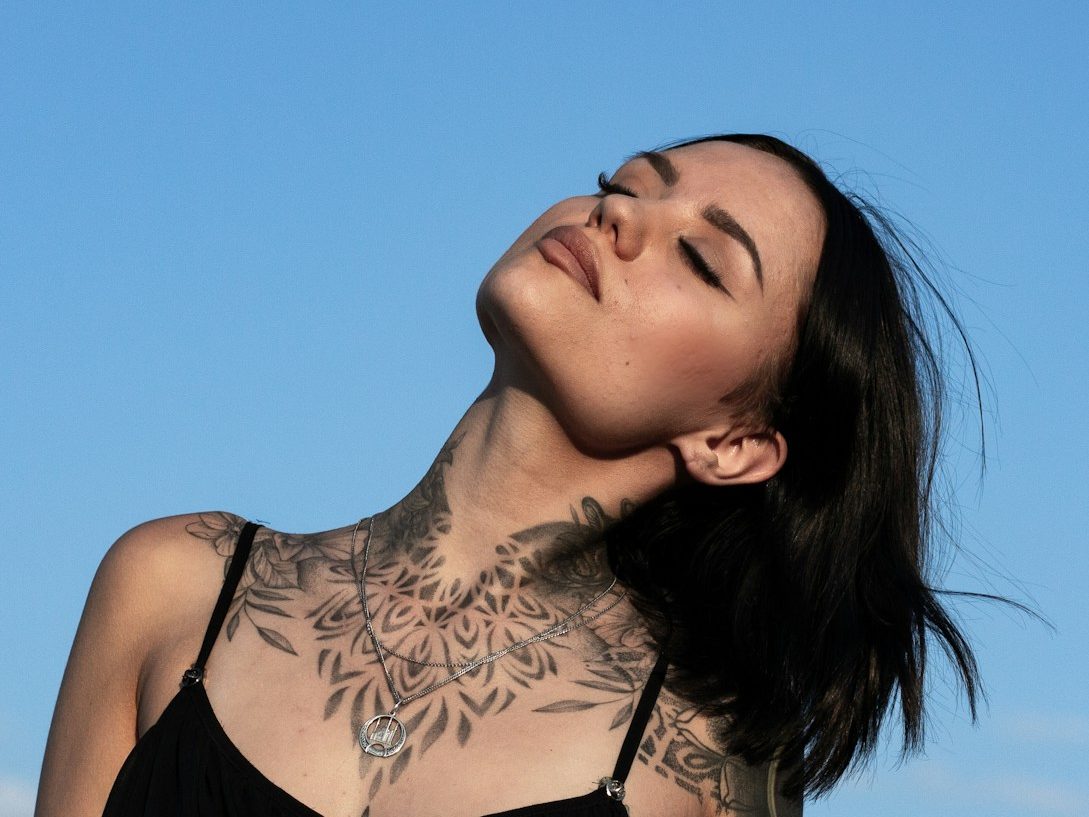 woman in black and white floral tank top with Dotwork-Tattoo.