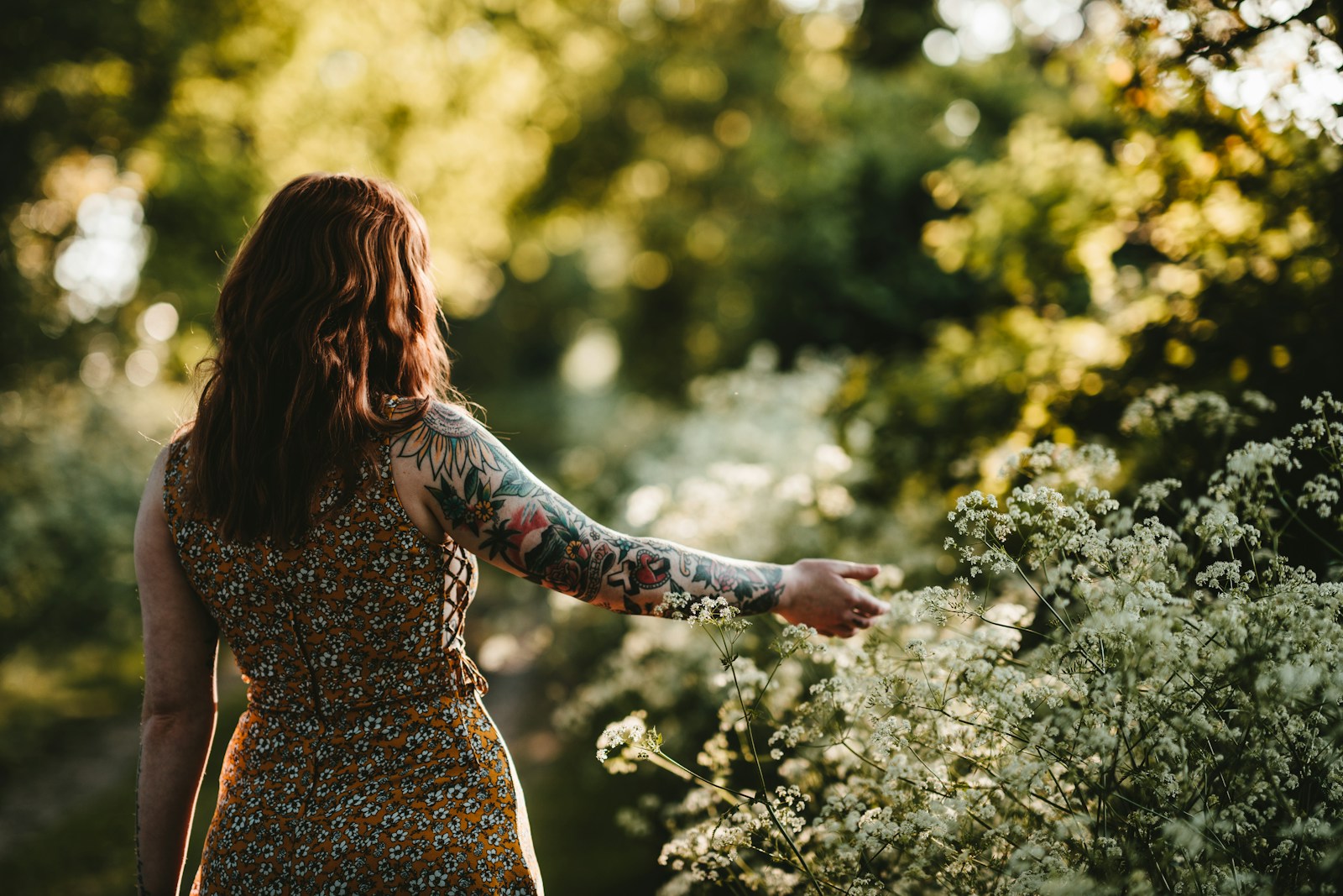 woman standing while holding white petaled flower selective focus photography_Sleeve-Tattoo