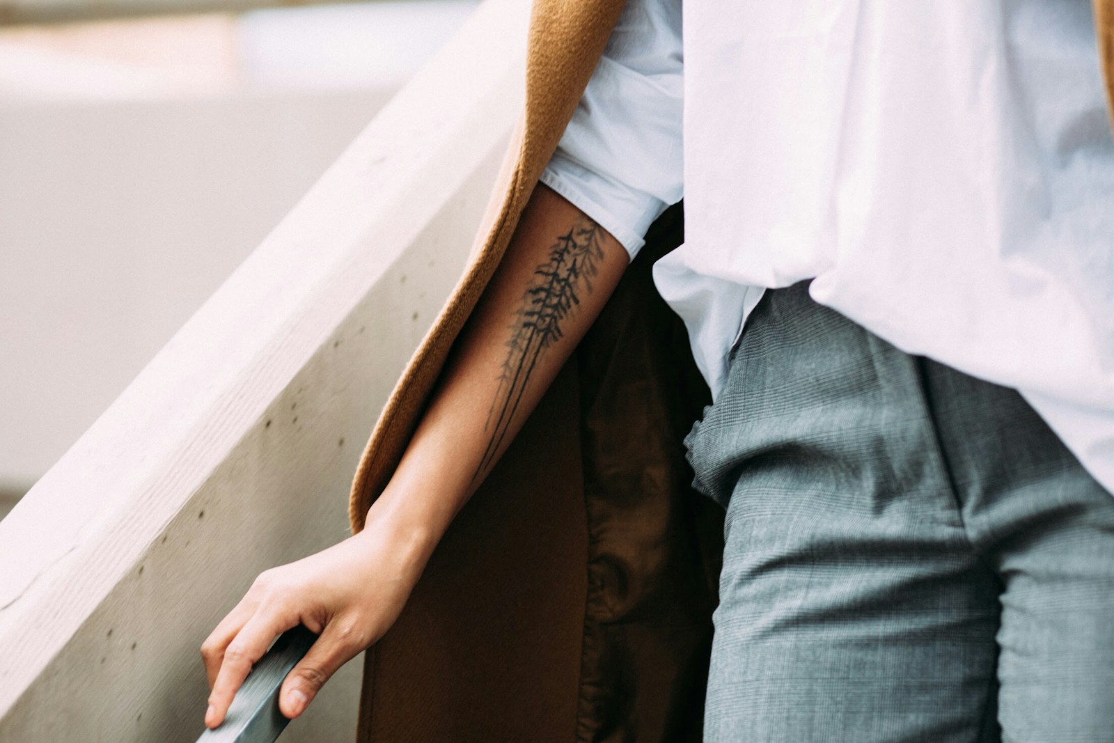 person holding gray handrail_Unterarm-Tattoo