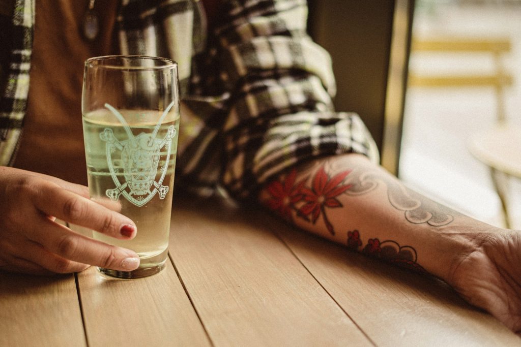 a person holding a glass of water. On her arm are Asian tattoos.
