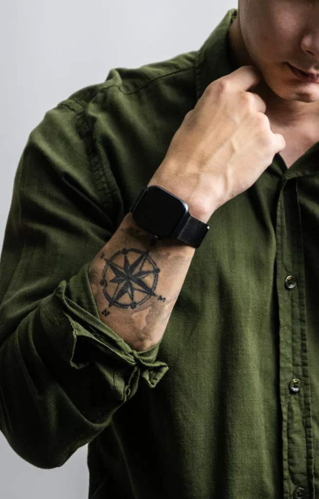 man in green button up shirt with black Apple Watch and a tattoo on his arm.