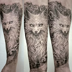 Dreigeteilte Nahaufnahme eines Unterarms mit einem Black-and-Grey-Tattoo. Das Tattoo zeigt einen Fuchs-Dämon im Japan-Tattoo-Stil.