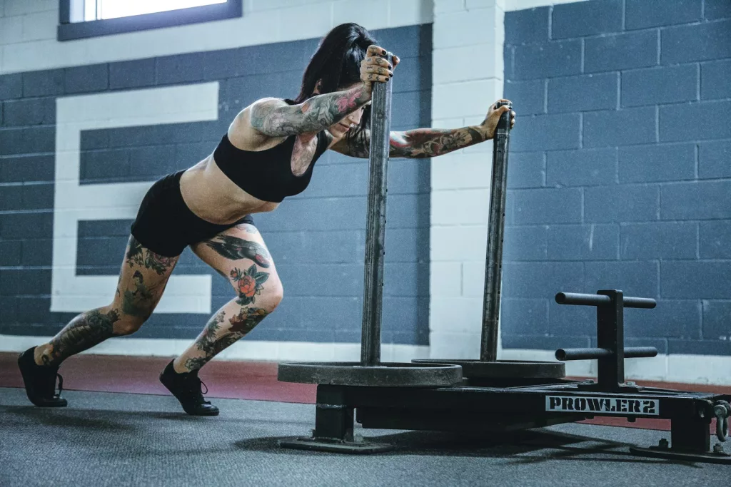 woman with tattoos on her arms and legs doing workout in room