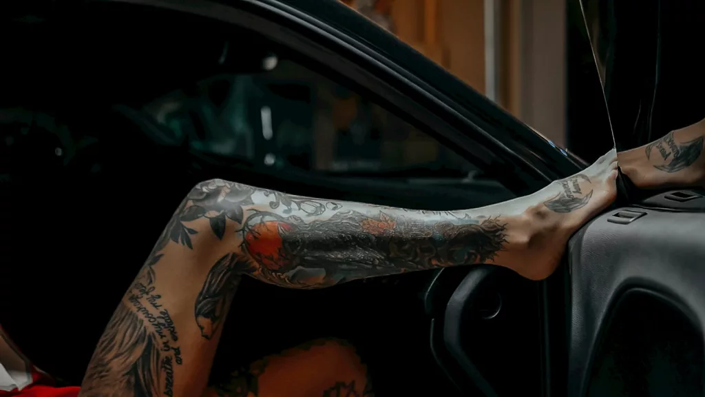 a person with tattoos sitting in a car
