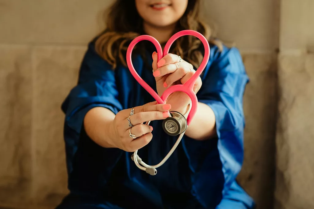 girl in blue jacket holding red and silver ring made of a stethoscope