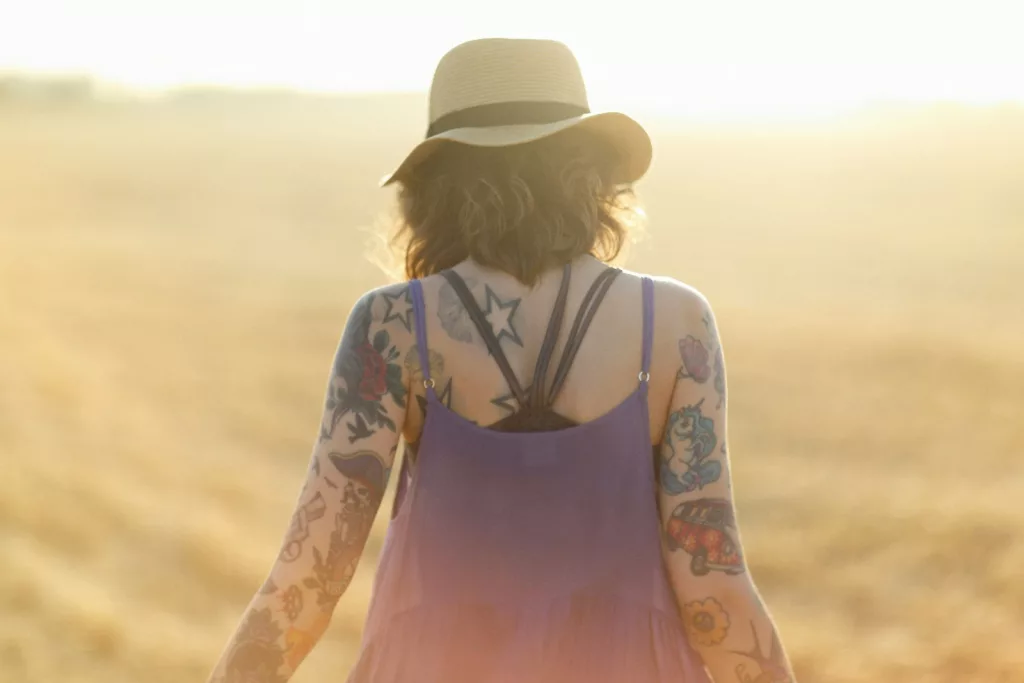 a woman in a hat walks through a field