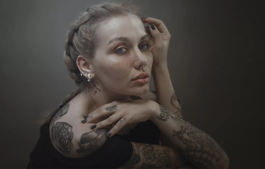 tattooed woman wearing black off-shoulder top posing