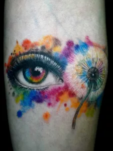 Nahaufnahme eines Watercolor-Tattoos: ein Auge und eine Pusteblume.
