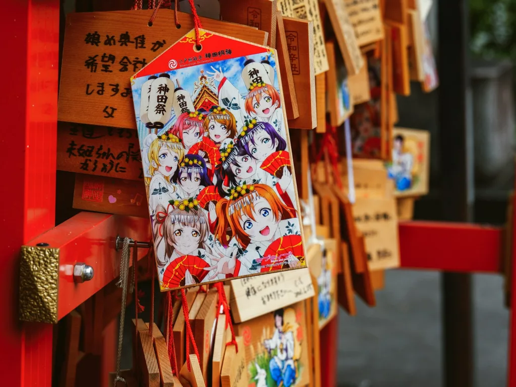 Ein Anhänger mit einem Anime-Bild an einem roten Holzgestell.