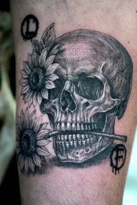 Nahaufnahme eines Unterarm-Tattoos in Blackand Grey. Ein Totenschädel mit Sonnenblumen.
