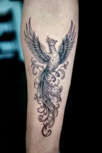 Nahaufnahme eines Unterarm-Tattoos. Das Schwarz-weiße Tattoo zeigt einen Phönix mit ausgebreiteten Schwingen.