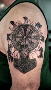 Nahaufnahme eines Oberarm-Tattoos in Black and grey. Das Tattoo zeigt Wikingermotive wie Runen.