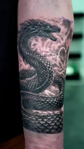 Nahaufnahme eines Drachen-Tattoos am Unterarm in Black and Grey.