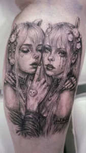 Nahaufnahme eines Unterschenkel-Tattoos in Black and grey. Zwei Mädchen. It Hasenschleifen in den Haaren.