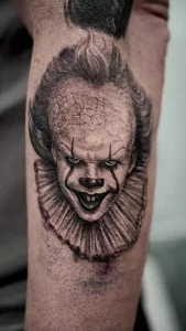 Nahaufnahme eines Unterarm-Tattoos in Black and Grey. Das Tattoo zeigt ein Porträt von Horrorclown Pennywise.