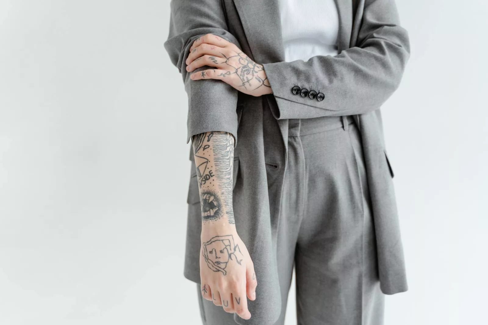 Close-up of a tattooed arm in a gray business suit, showcasing detailed ink designs.