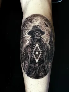 Nahaufnahme eines Unterschenkel-Tattoos in Black and Grey. Das Motiv zeigt ein Cowboy-Skelett mit Pistolen vor düsterem Hintergrund. Auf den Rippen ist die HSV-Raute zu sehen.